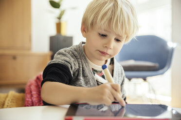 Porträt eines kleinen Jungen, der mit einem digitalen Stift auf einem digitalen Tablet zu Hause zeichnet - MFF001630