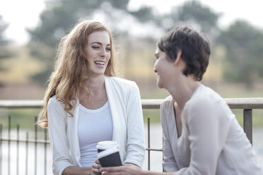 Zwei Frauen mit Kaffee zum Mitnehmen auf der Terrasse eines Restaurants - ZEF005098