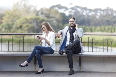 Pärchen mit Smartphones auf einer Terrasse - ZEF005101