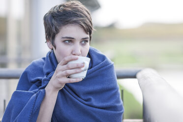 Woman with blue blanket drinking coffee - ZEF005108