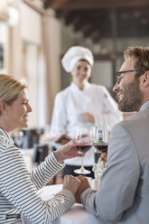Mid adult couple in restaurant toasting with redwine - ZEF005155