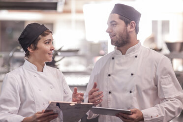 Two chefs working together in kitchen, using digital tablet - ZEF005177