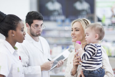 Apothekerin, die einer Kundin in einer Drogerie mit einem Baby hilft - ZEF005893