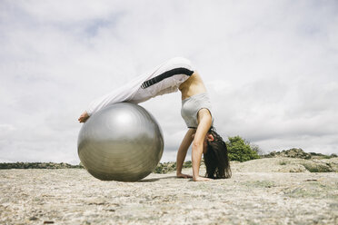 Frau übt Yoga im Freien mit Gymnastikball - ABZF000054