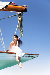 Brunette young woman on a sailing trip sitting on bow - TOYF000812