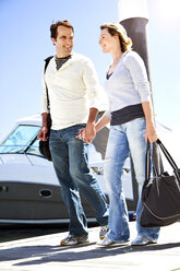 Mature couple walking hand in hand on jetty - TOYF000813