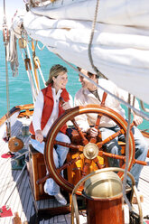 Happy mature couple at helm of a sailing ship - TOYF000821