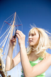 Young woman taking a cell phone picture on a sailing ship - TOYF000941