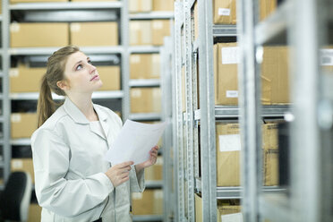 Young woman in storehouse looking up - SGF001622