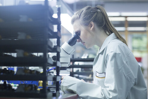 Technician examining circuit board with microscope - SGF001628