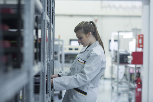 Young woman at shelf in storehouse - SGF001630