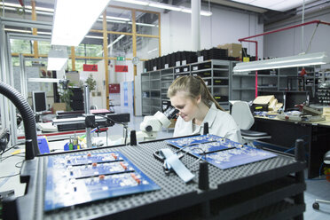 Technician examining circuit board with microscope - SGF001640
