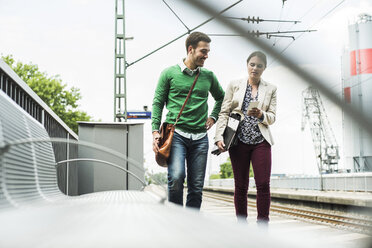 Young man and woman with cell phone on railway platform - UUF004492