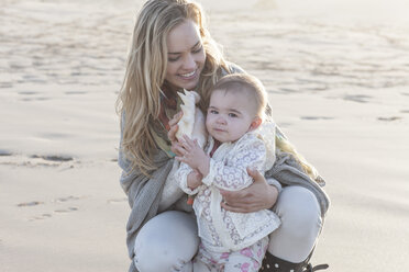 Mother and baby girl with shell on the beach - ZEF005257