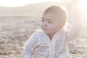 Porträt eines kleinen Mädchens, das die Hand seiner Mutter hält, am Strand bei Gegenlicht - ZEF005259