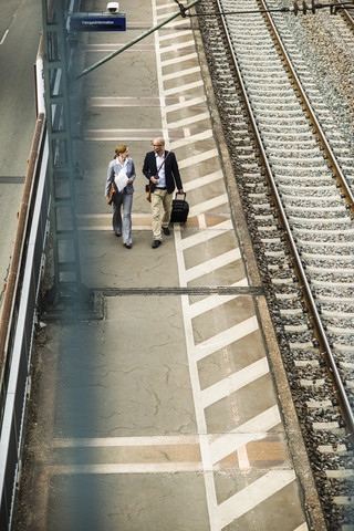 Geschäftsmann und Geschäftsfrau gehen auf dem Bahnsteig, lizenzfreies Stockfoto