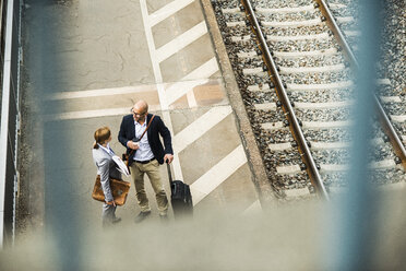 Geschäftsmann und Geschäftsfrau im Gespräch auf dem Bahnsteig - UUF004419