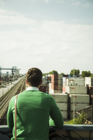 Mann im Freien mit Blick auf den Güterbahnhof, lizenzfreies Stockfoto