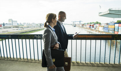 Businessman and businesswoman talking on bridge - UUF004451