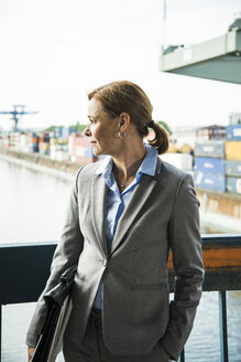 Geschäftsfrau im Containerhafen mit Blick zur Seite - UUF004453