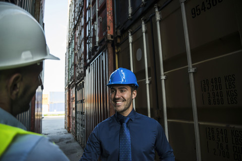 Zwei Männer mit Schutzhelmen im Containerhafen, lizenzfreies Stockfoto