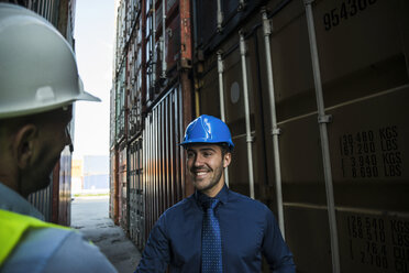 Two men with safety helmets at container port - UUF004464