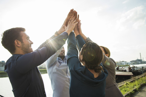 Four happy businesspeople raising their hands together stock photo