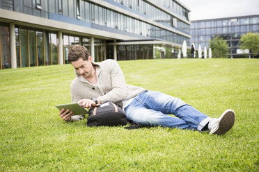 Deutschland, Tübingen, junger Mann entspannt auf einer Wiese mit digitalem Tablet - LVF003544