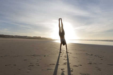 Südafrika, Kapstadt, Silhouette einer jungen Frau im Handstand am Strand, lizenzfreies Stockfoto