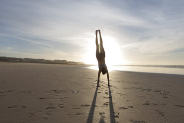 Südafrika, Kapstadt, Silhouette einer jungen Frau im Handstand am Strand - ZEF005204