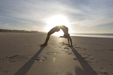 South Africa, Cape Town, silhouette of young woman in bridge position on the beach - ZEF005206