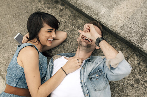 Laughing young couple lying on the ground outside - MGOF000247