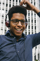 Lächelnder junger Mann mit Kopfhörern im Freien - ABZF000067