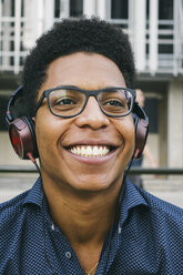 Lächelnder junger Mann mit Kopfhörern im Freien - ABZF000071
