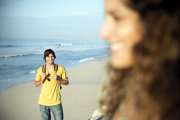 Südafrika, lächelnder Mann, der am Strand steht und seine Freundin beobachtet - TOYF000991