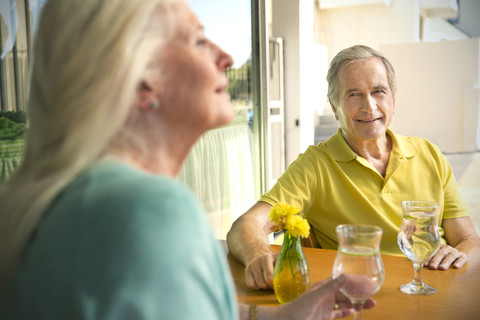 Porträt eines lächelnden älteren Mannes, der seine Frau in einem Café beobachtet, lizenzfreies Stockfoto