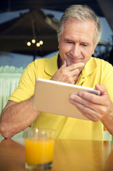 Porträt eines älteren Mannes, der in einem Café sitzt und ein digitales Tablet benutzt - TOYF000997