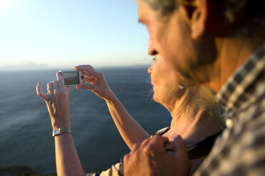 Südafrika, älteres Paar fotografiert das Meer bei Sonnenuntergang - TOYF001004