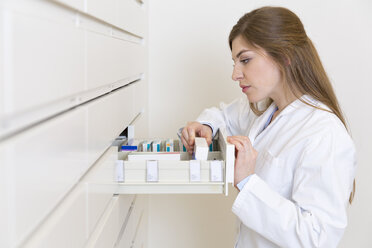 Female pharmacist searching drug in a drawer cabinet - FKF001059