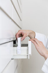 Hands of pharmacist taking drug from a drawer cabinet - FKF001064