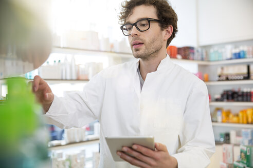 Porträt einer Apothekerin bei der Bestandskontrolle mit digitalem Tablet - FKF001068