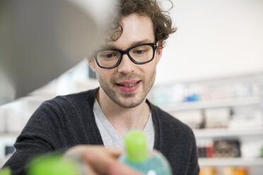 Portrait of man comparing products in a pharmacy - FKF001073