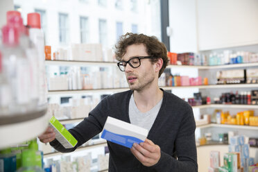 Man comparing products in a pharmacy - FKF001074