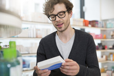 Portrait of man looking at product in a pharmacy - FKF001075