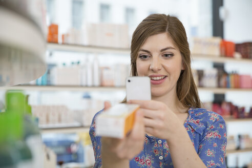 Portrait of woman comparing products in a pharmacy - FKF001076
