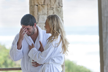 Glückliches junges Paar im Bademantel in einem Strandhaus - ZEF005342