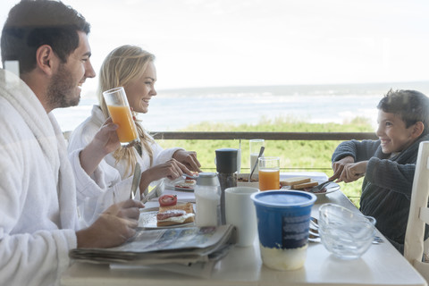 Familie auf der Veranda des Strandhauses beim Frühstück, lizenzfreies Stockfoto