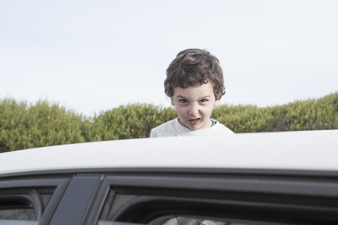 Boy looking through a sunroof of a car stock photo