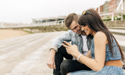 Spain, Gijon, young couple in love looking at smartphone - MGOF000252