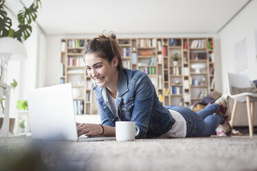 Junge Frau benutzt Laptop zu Hause - RBF002871